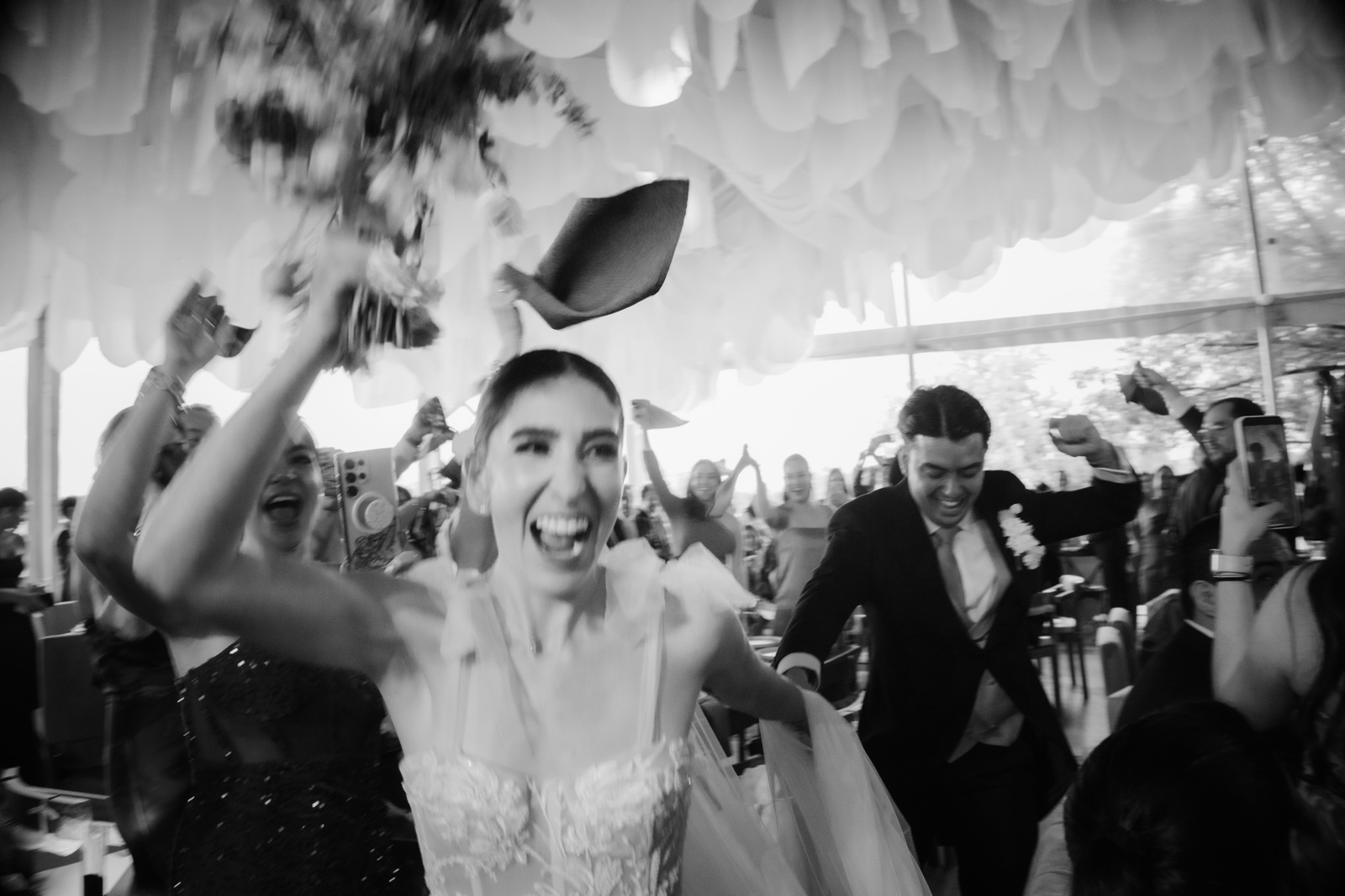 novia sonriente rodeada de invitados, en blanco y negro