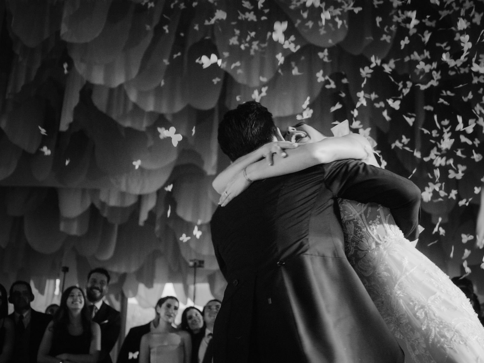 abrazo de los novios entre confeti, en blanco y negro
