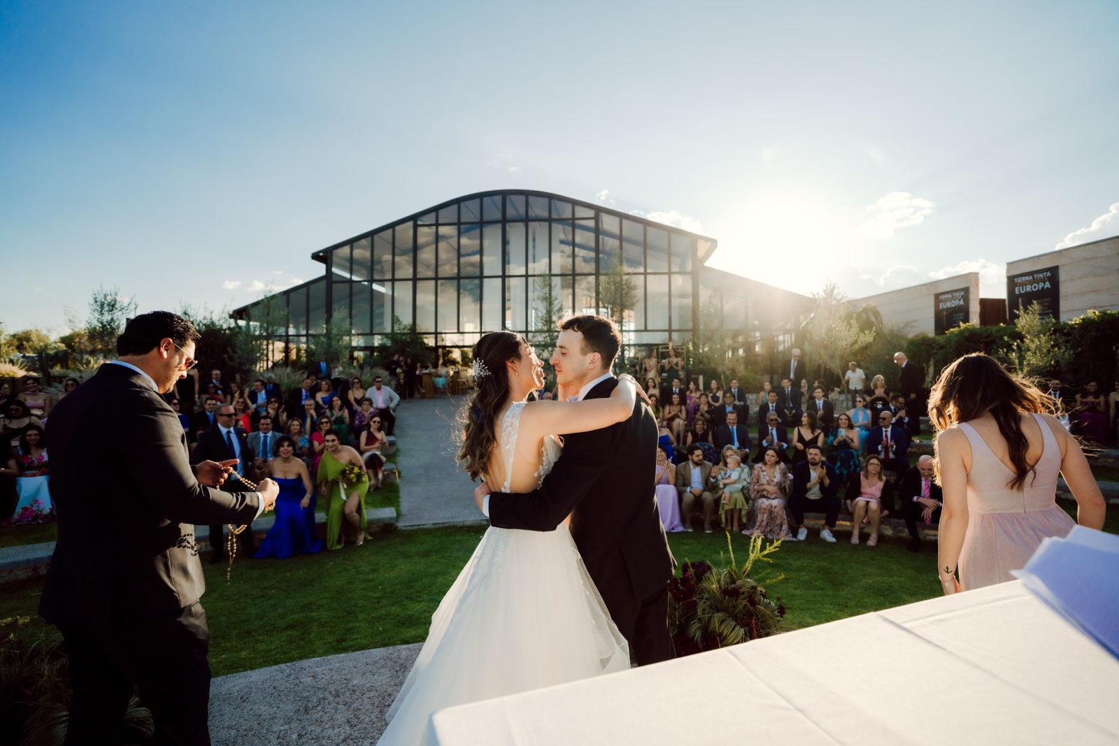 novios abrazados entre sus invitados al atardecer