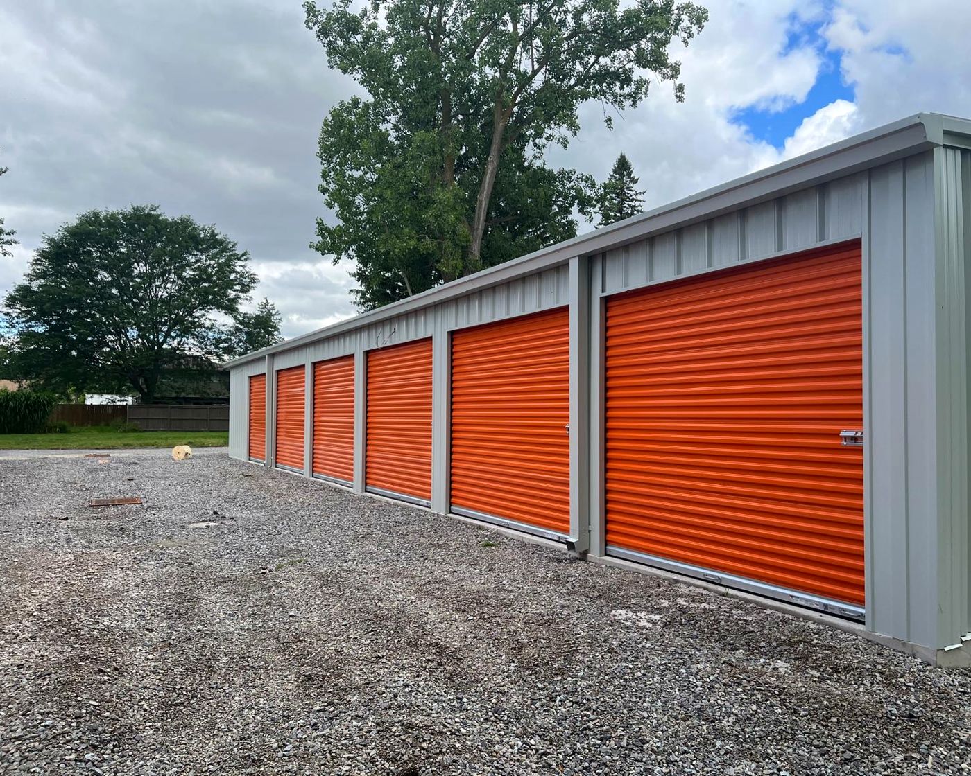 Row of brand new drive up storage units with orange roll up doors at HJ Storage in Niagara Falls