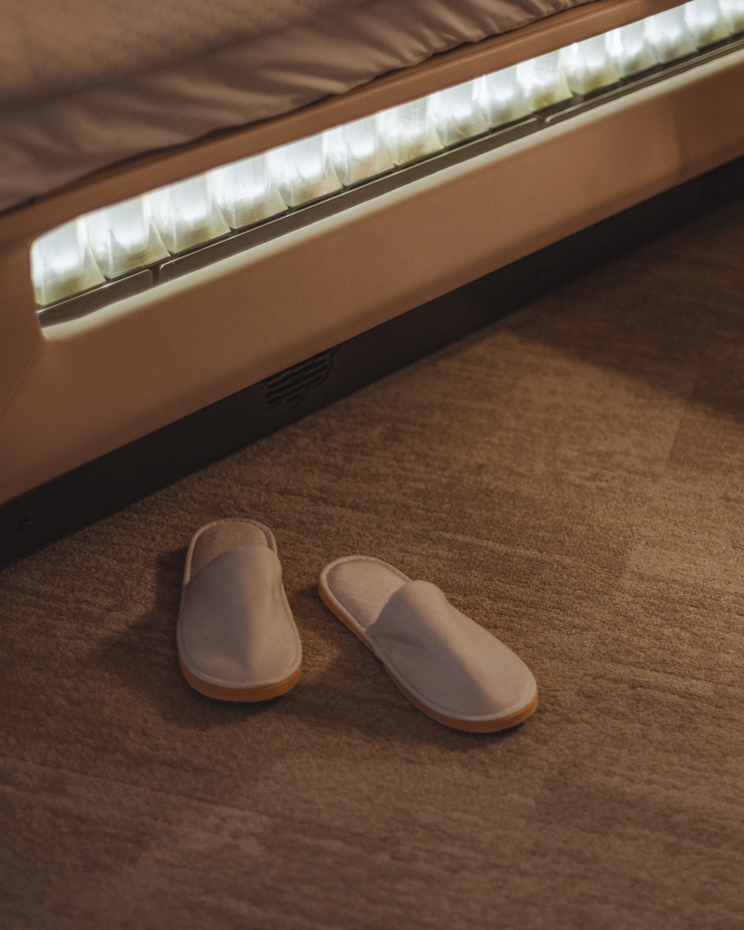 Slippers on the carpet beside the lit base of the Sleep System