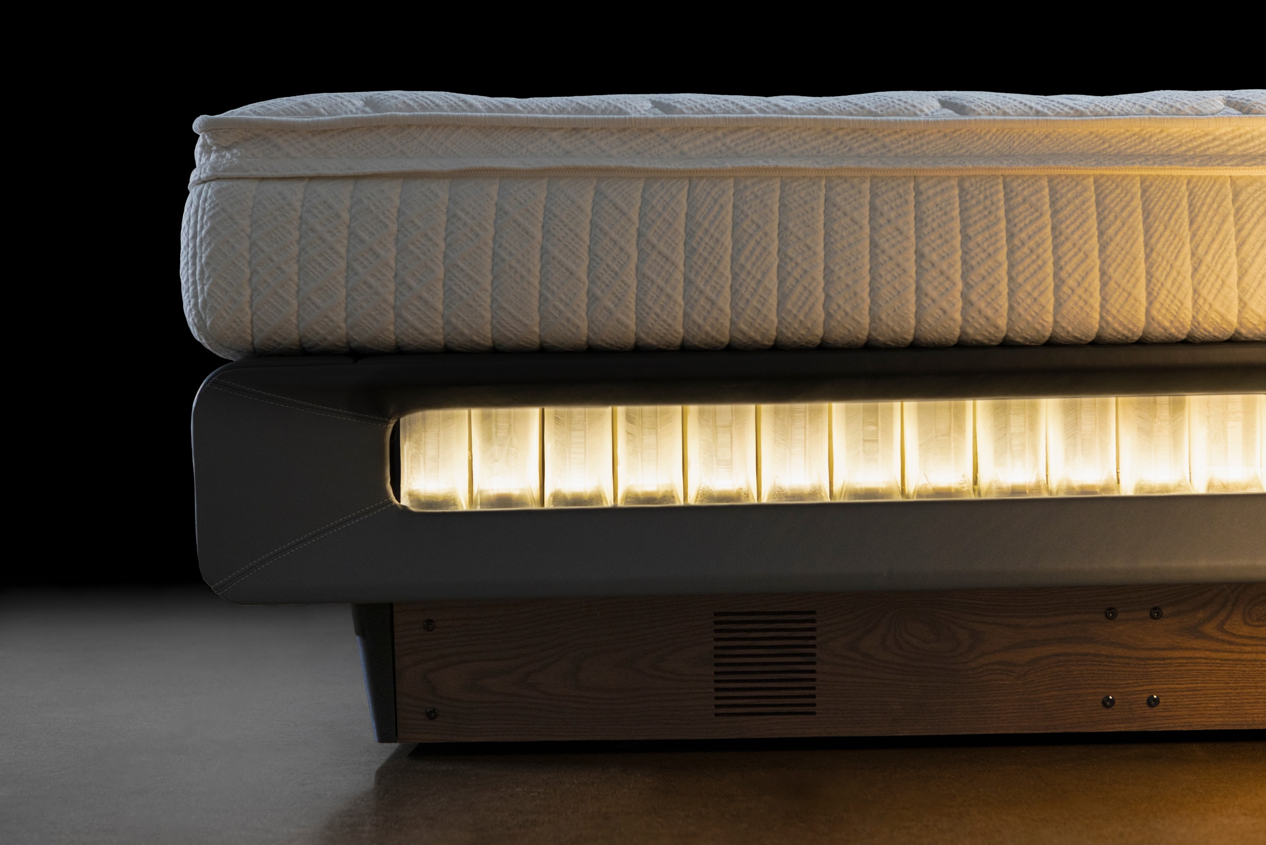 The sleep surface lifted clear of the lit row of Smart Springs beneath it