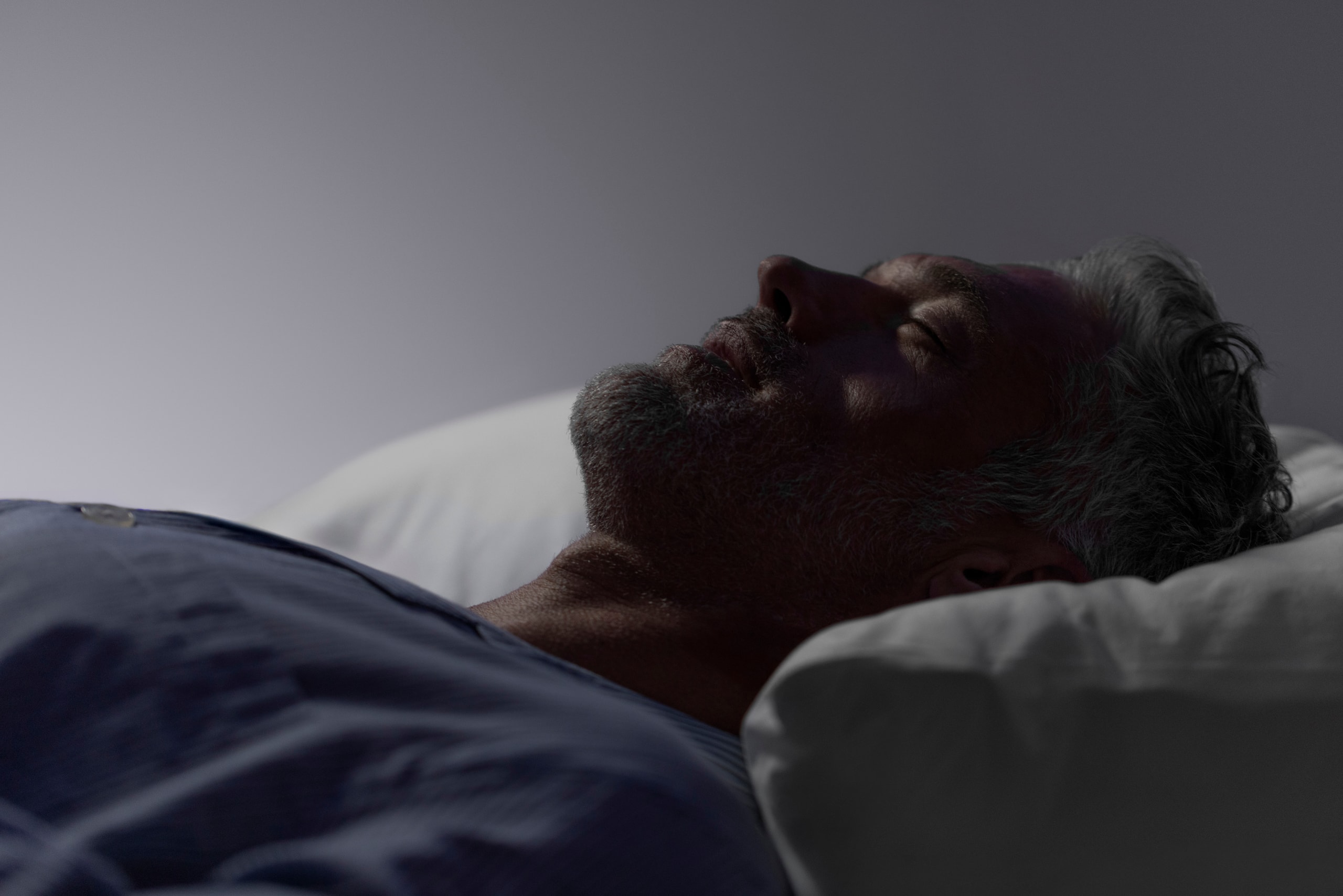 A sleeper on their back in the blue light before dawn