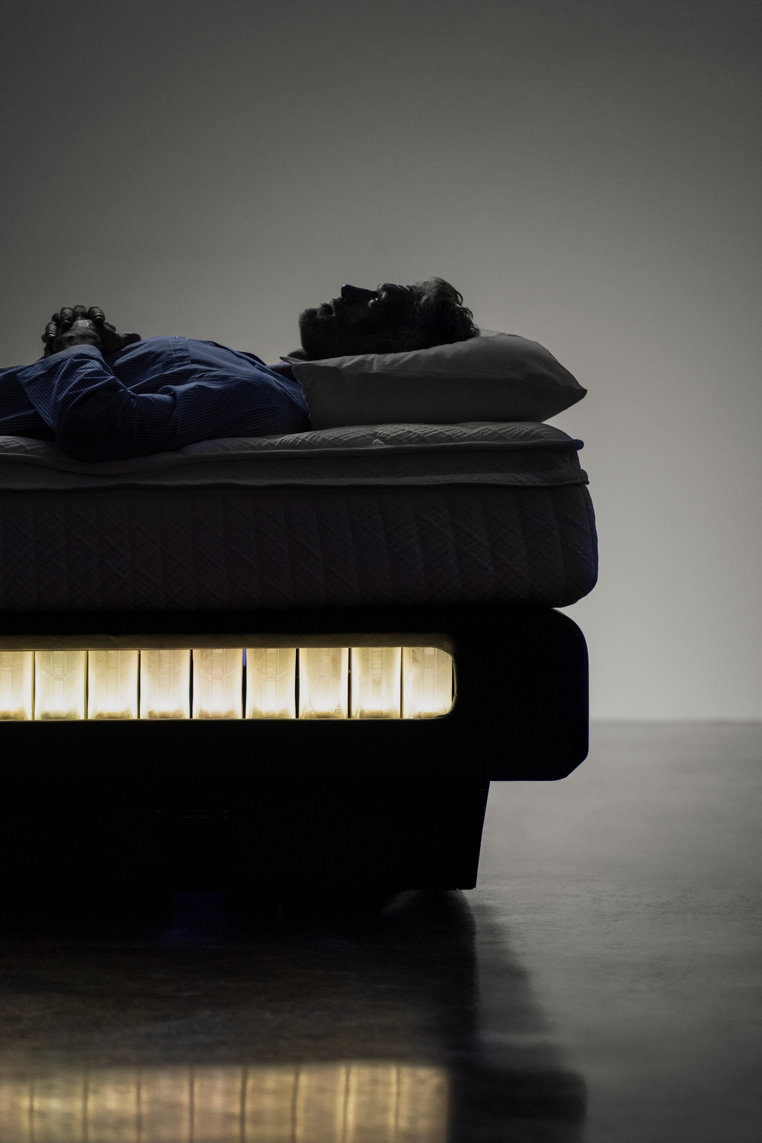 Two sleepers on the Sleep System in profile, the lit row of Smart Springs glowing beneath the bed