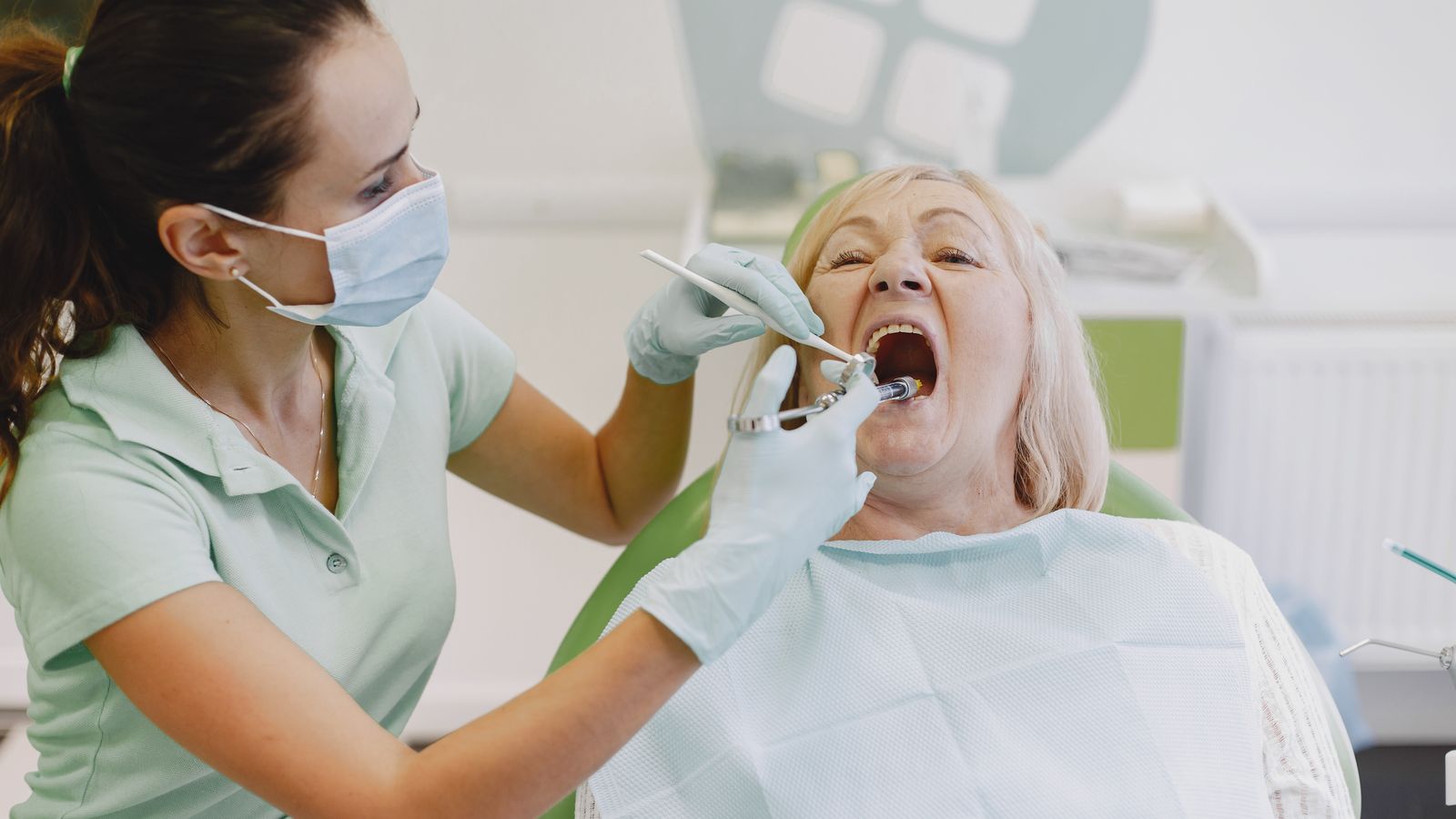 A female dentist examines a senior woman patient in a dental clinic setting