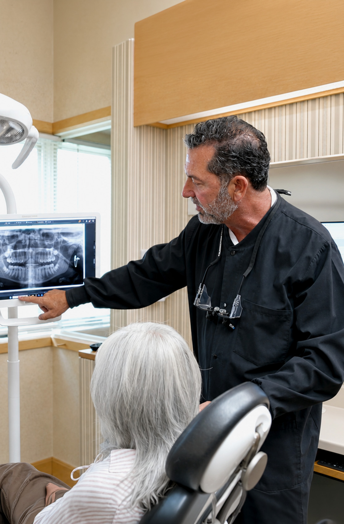 Dr. Kenneth J. Bevan reviewing a digital X-ray with a patient during a dental exam in Napa, CA