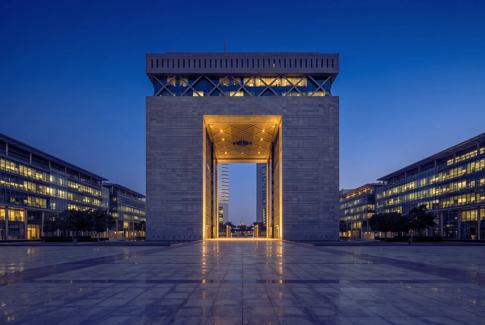 The Gate at DIFC at blue hour, its arch lit gold above an empty stone plaza