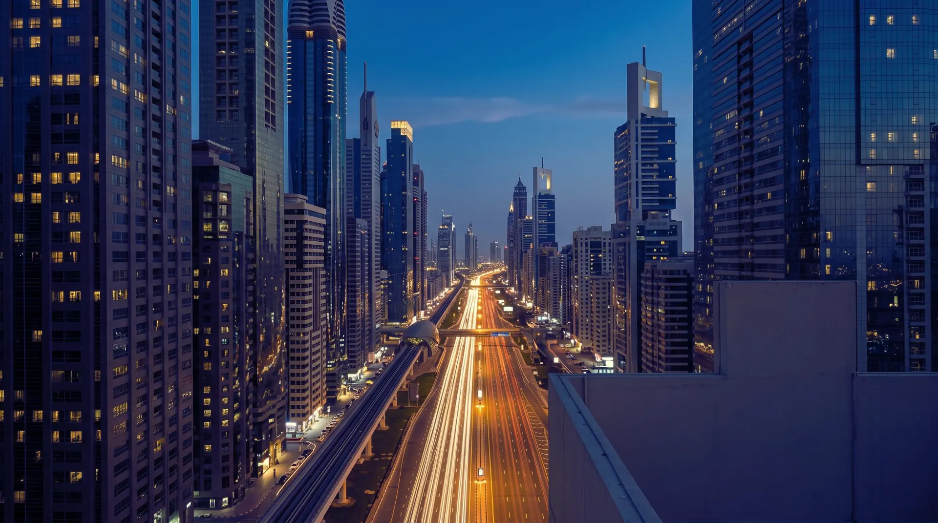 Sheikh Zayed Road at blue hour from above, traffic drawn into ribbons of gold light