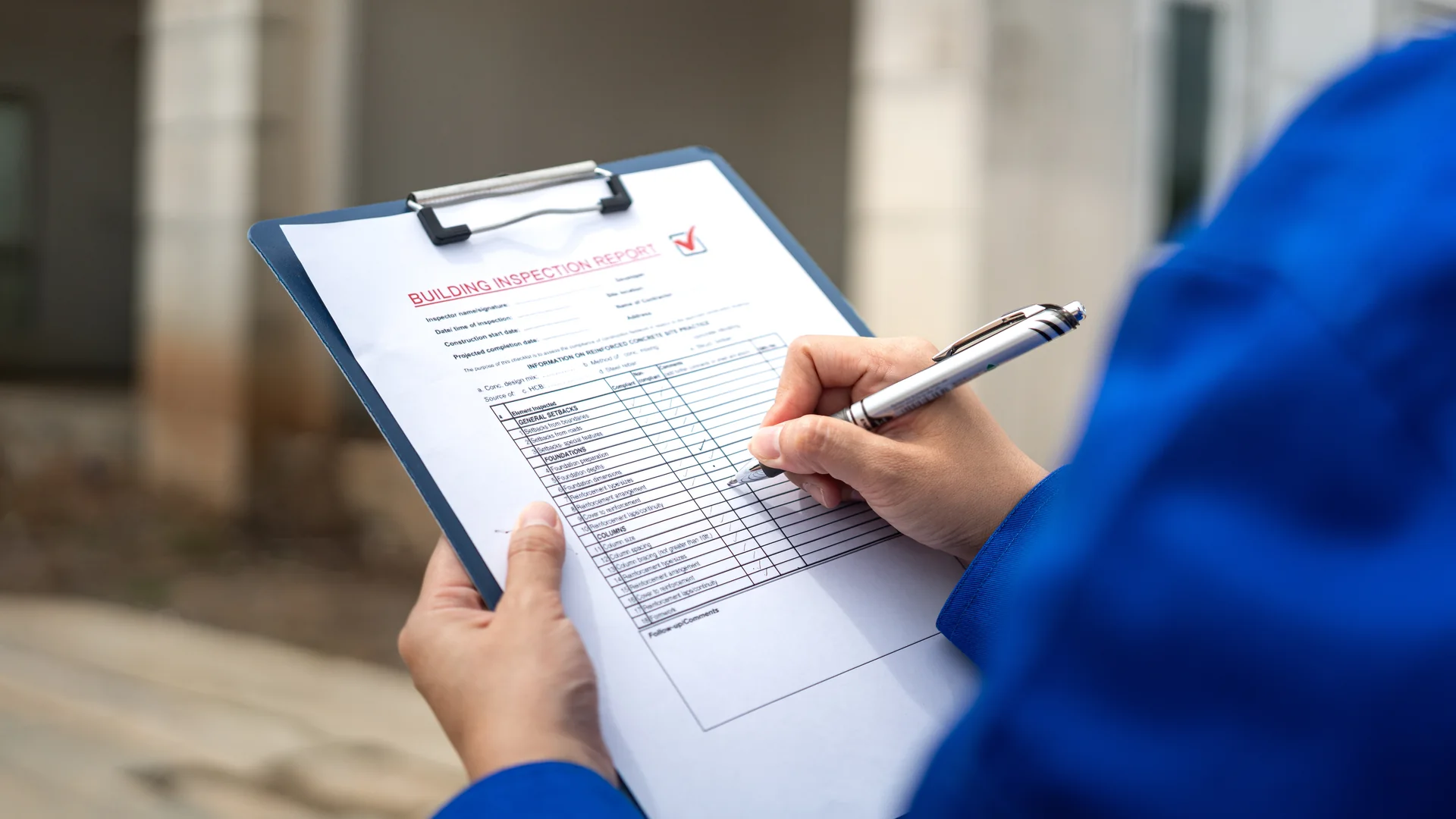 An adjuster filling out a building inspection report on a clipboard