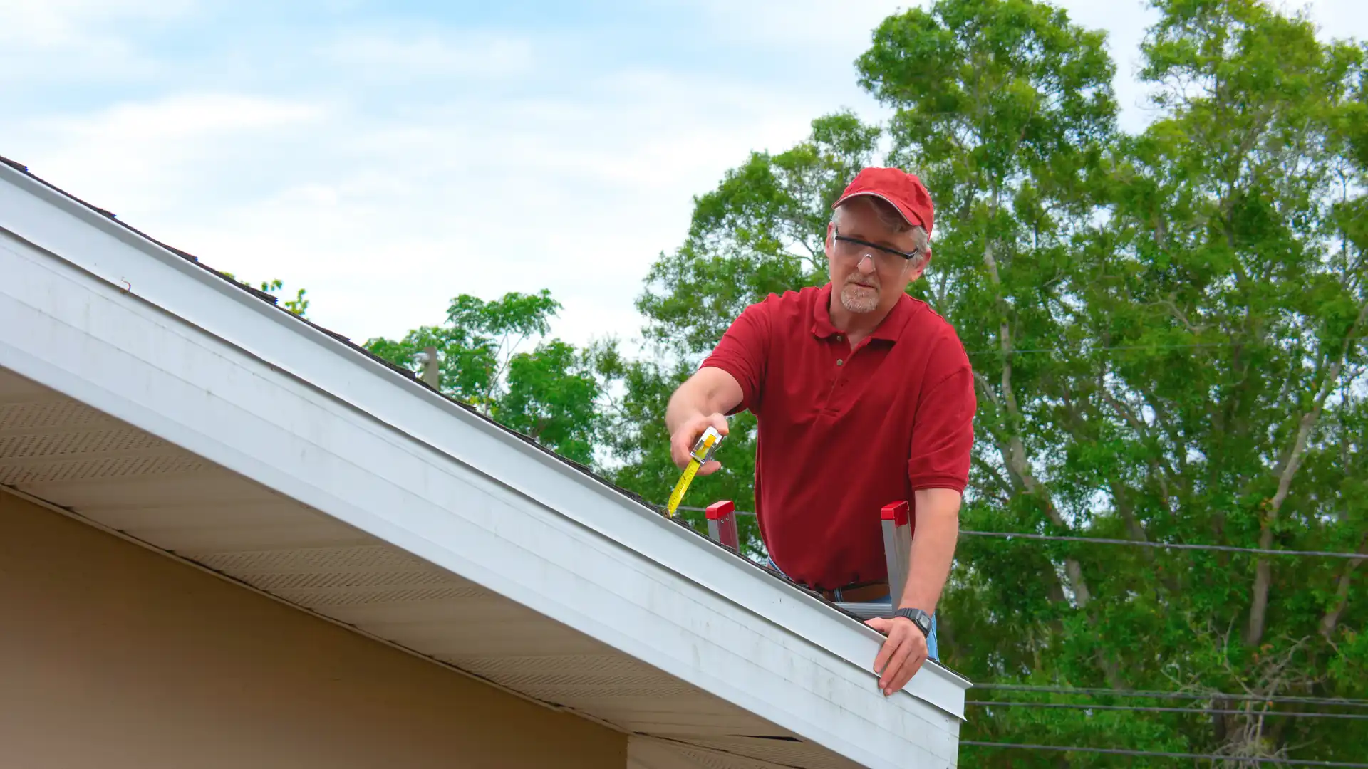 An adjuster on a ladder measuring the roof edge during a property inspection