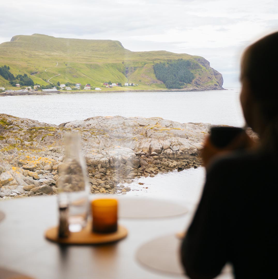 En kvinne som ser på utsikten fra en av hyttene på Runde leid ut av Runde panorama.