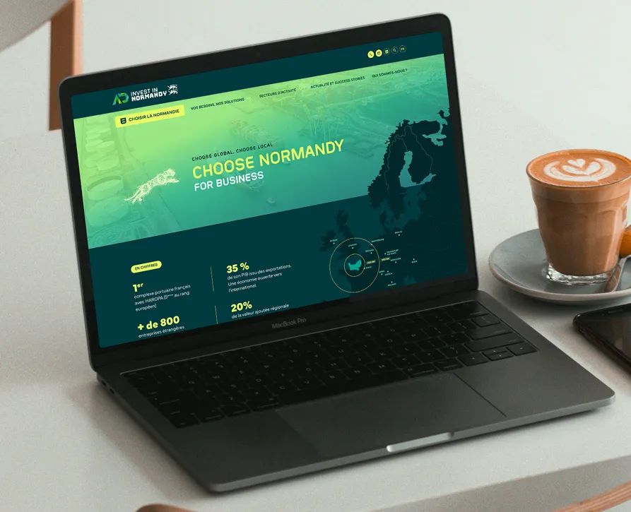 Site Invest in Normandy sur ordinateur portable à côté d'un café
