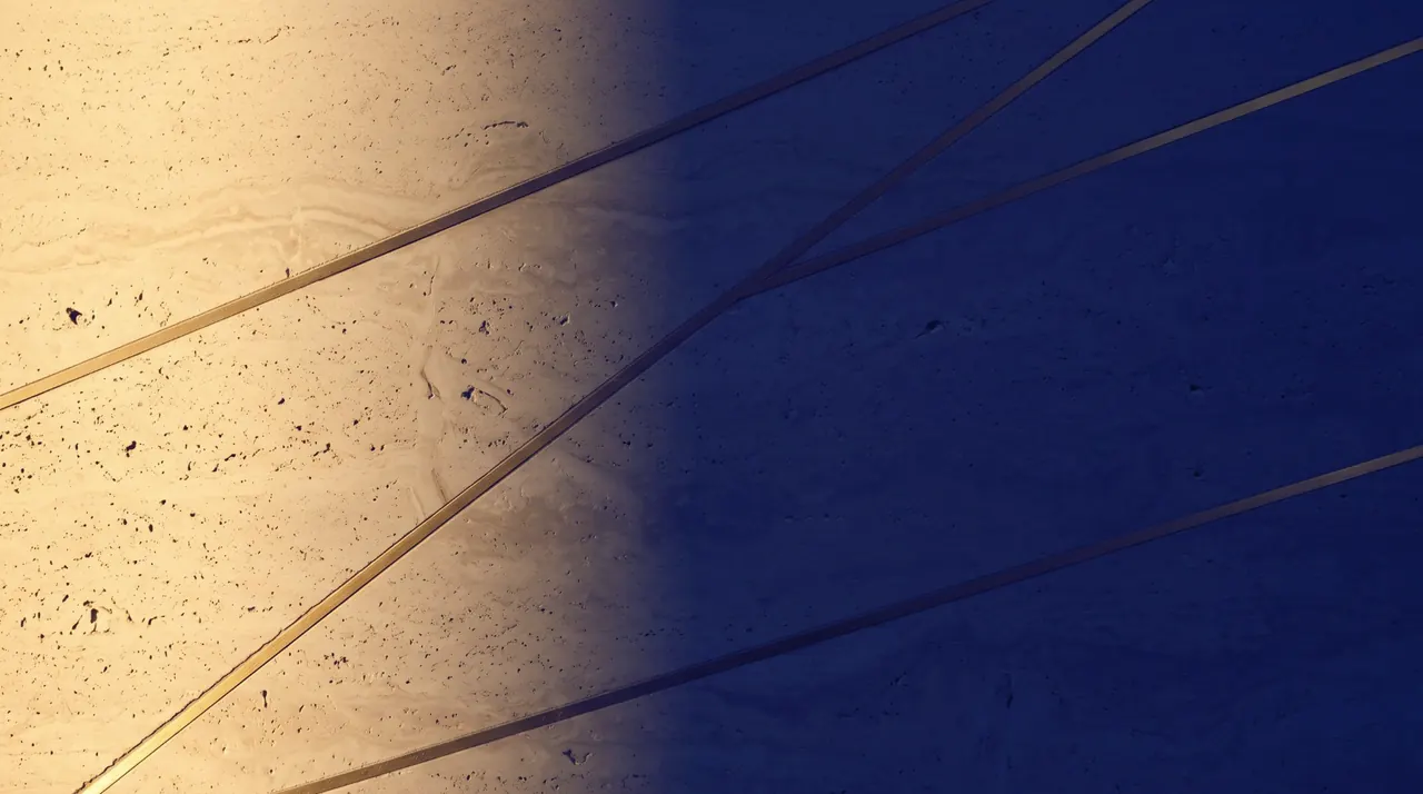 Honed travertine inlaid with thin gold lines, lit from one side