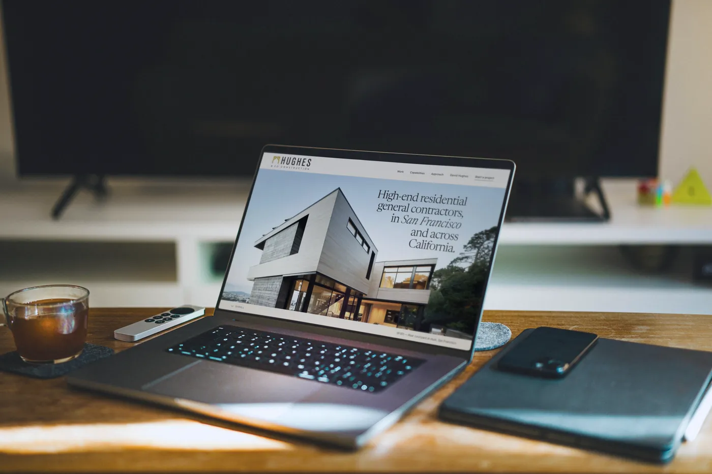 Our Hughes & Co. redesign concept on a MacBook Pro on a sunlit wooden table.