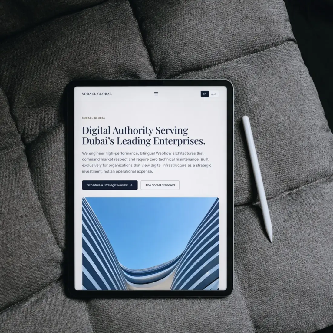 The Sorael Global English homepage on a tablet in portrait orientation, lying on quilted grey fabric.