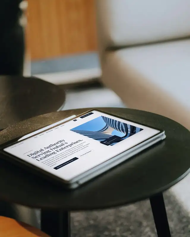 The Sorael Global homepage on a tablet, resting on a dark side table beside a sofa.