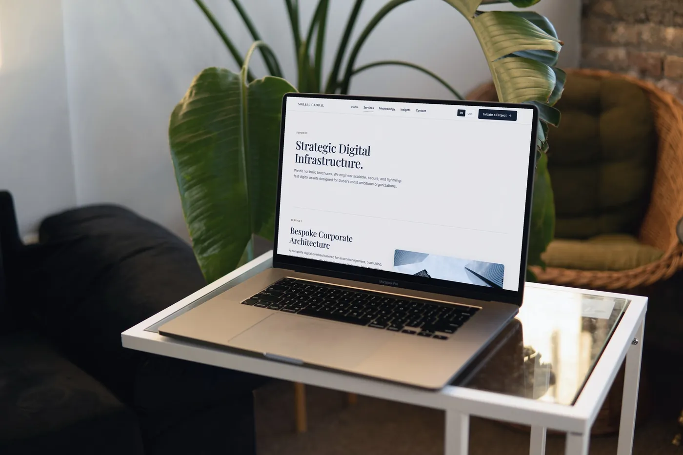 The Sorael Global Services page on a laptop on a glass table, among house plants.