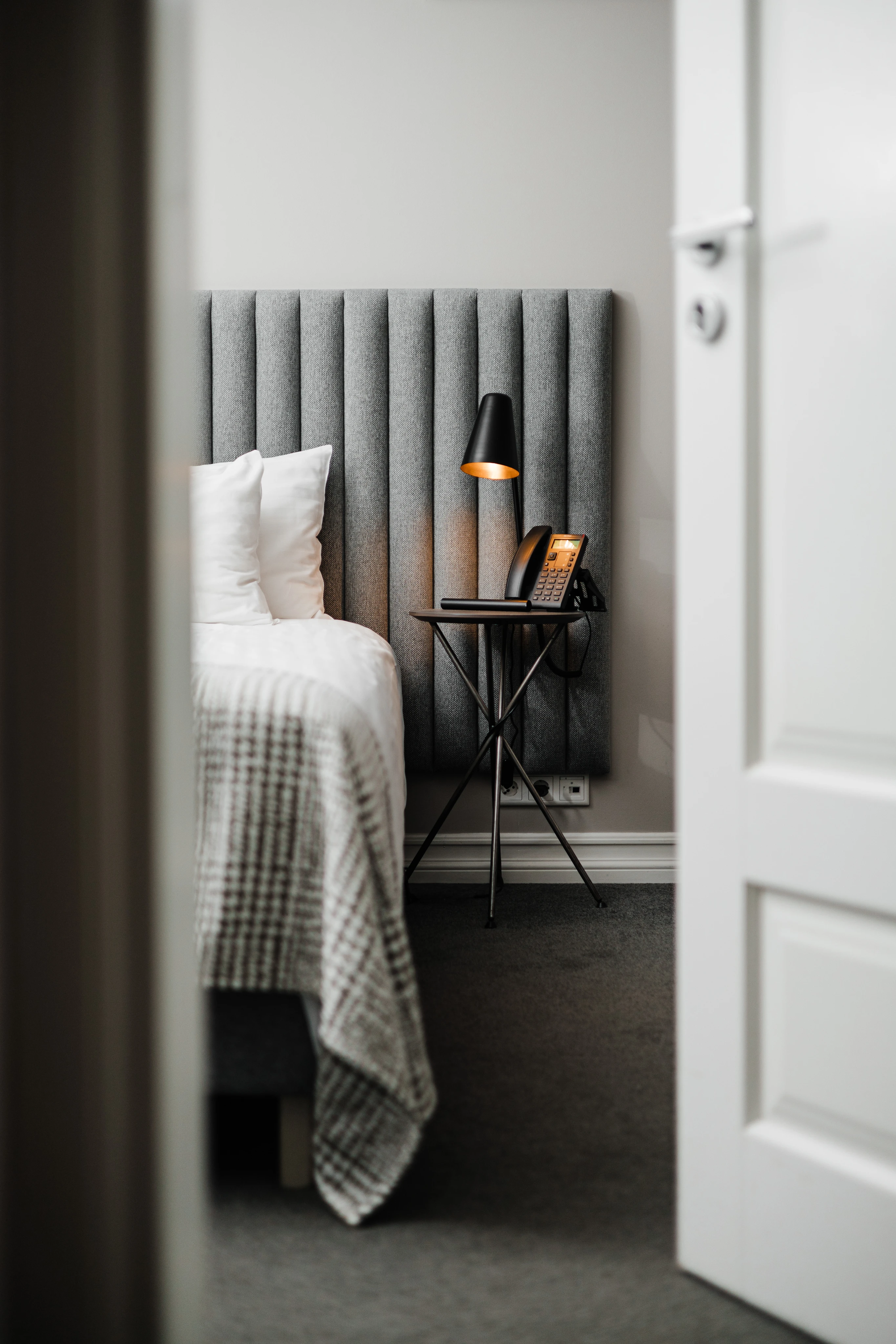 Hotel room with a bed, a bedside lamp and a telephone on a side table