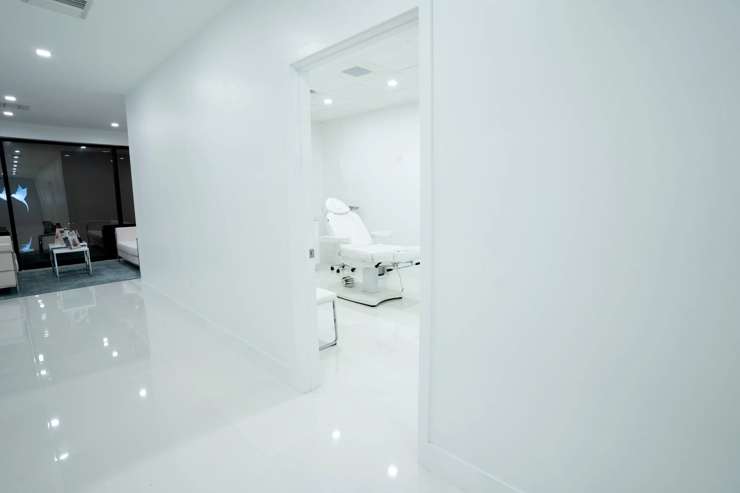 Open doorway revealing a white treatment chair off the main hallway at Cosmetica Med Spa