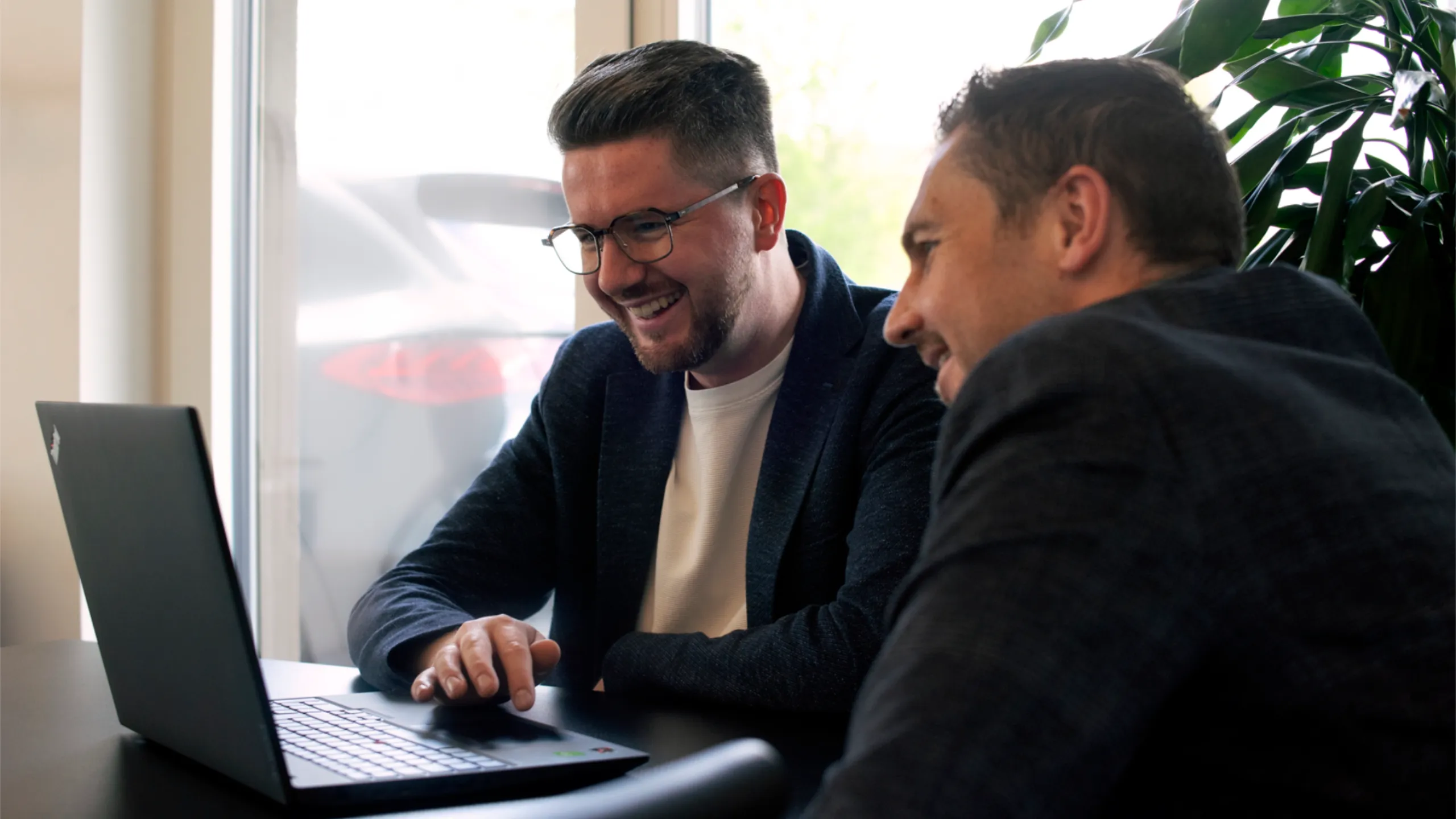 Zwei Mitarbeiter von PORTFORMANCE arbeiten gemeinsam am Laptop
