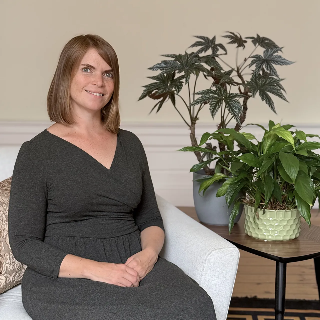 Ellinor, psychodynamic counsellor, sitting in a chair in her Edinburgh counselling room beside house plants