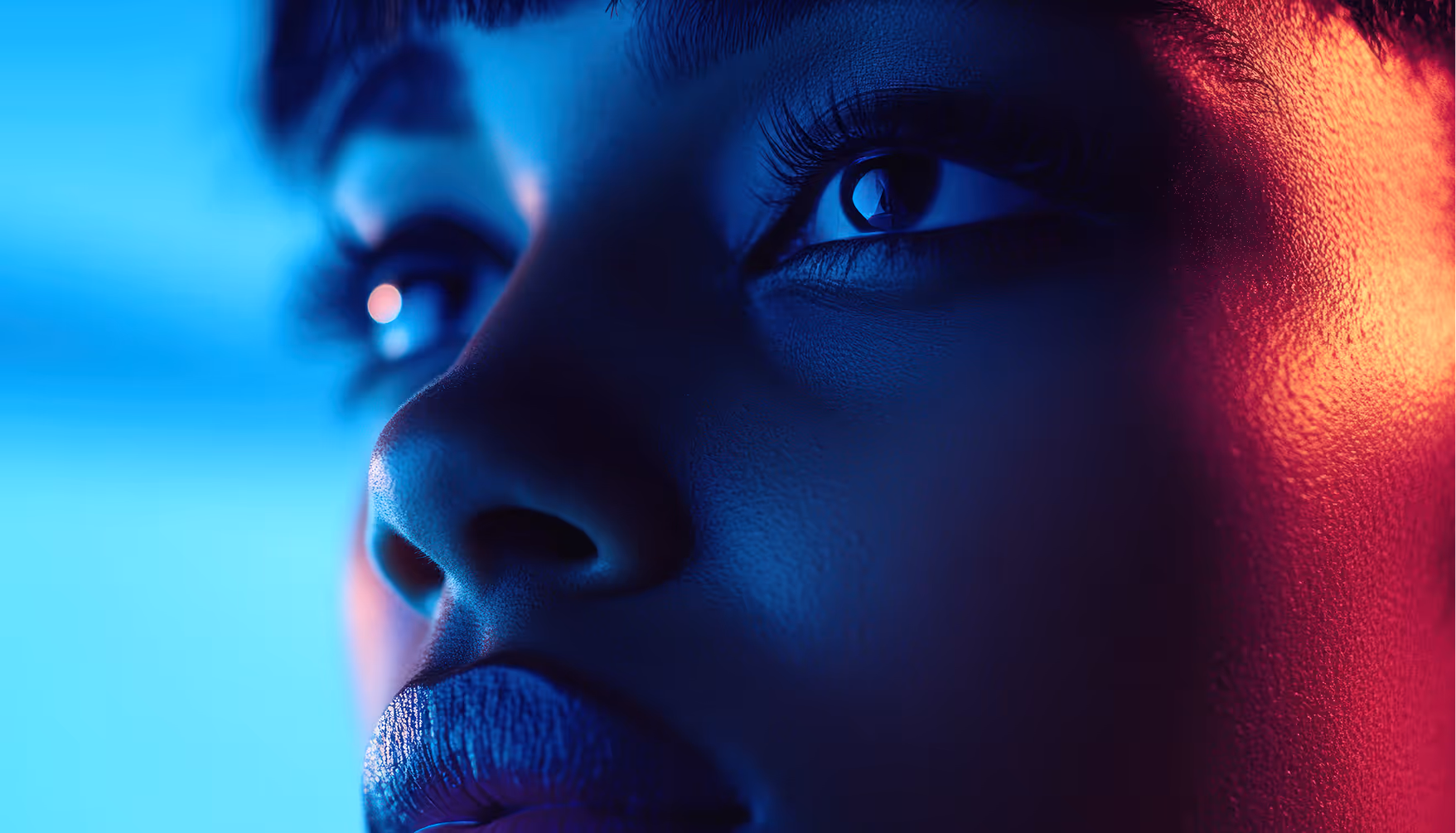 Close-up of a face lit with blue and red neon lighting, showing eyes, nose, and lips in detail.