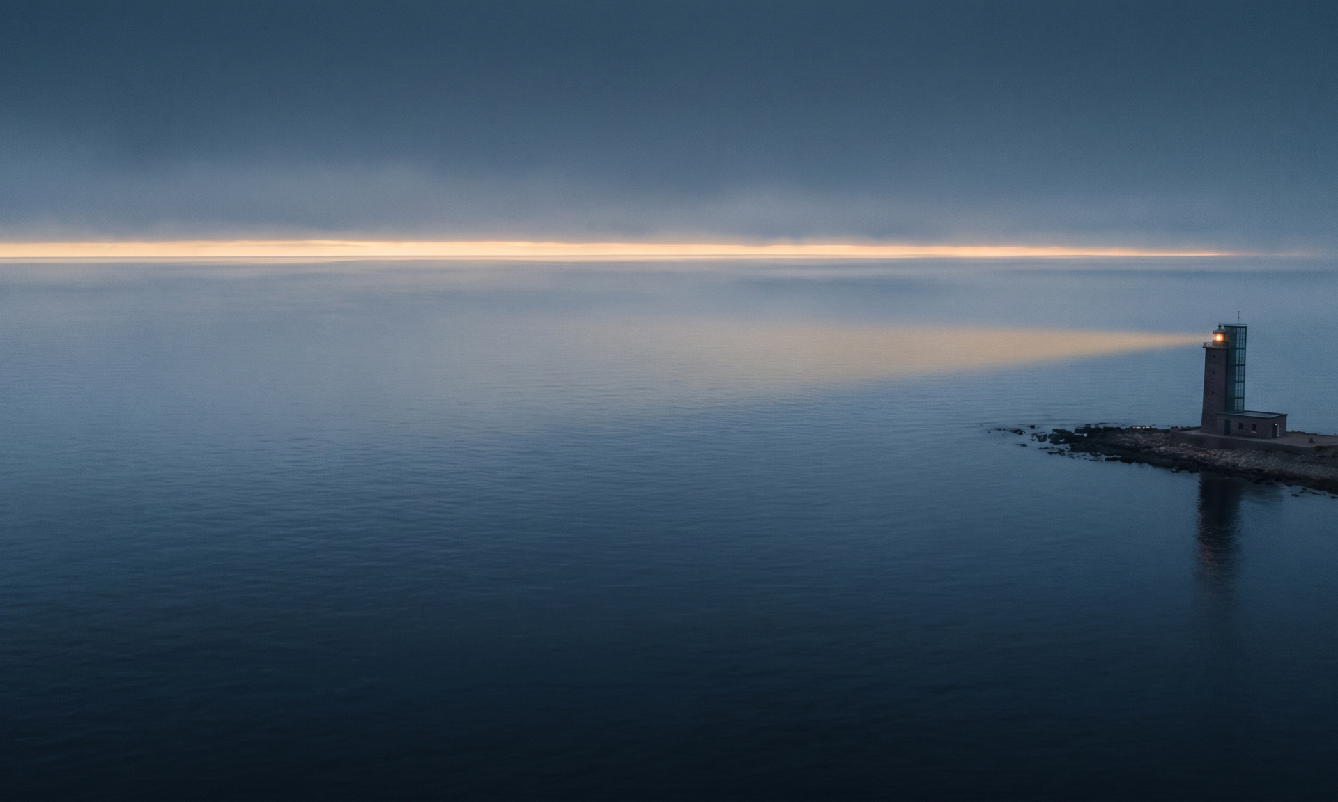 Leuchtturm am Horizont bei Dämmerung