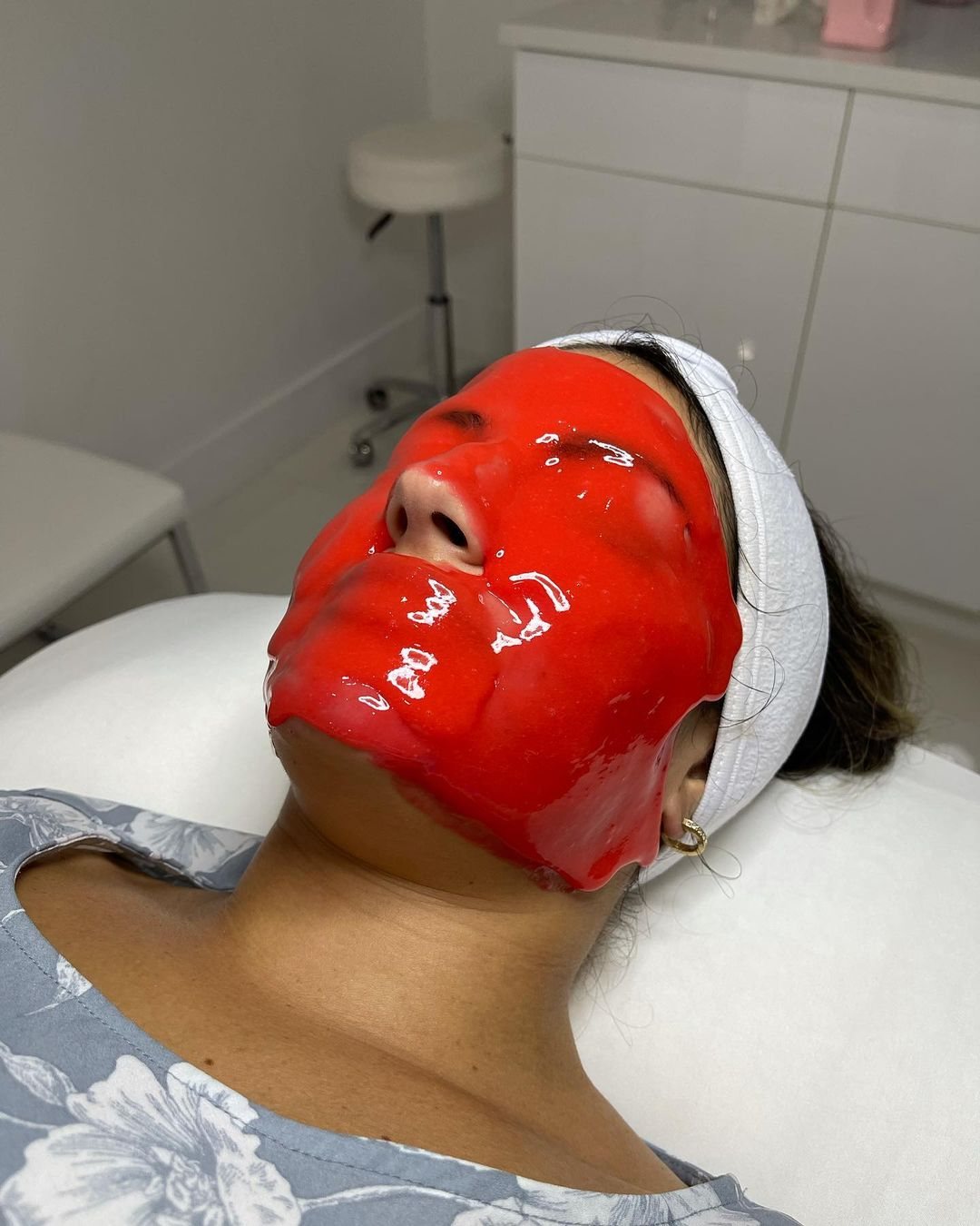 Client wearing a red jelly mask during a facial at Cosmetica Med Spa