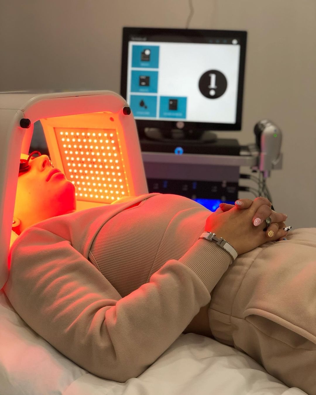 Client relaxing under an LED light panel during a Hydrafacial at Cosmetica Med Spa