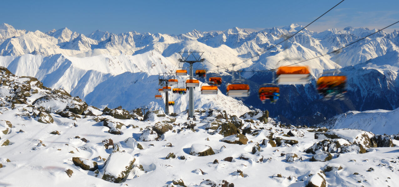 Sessellift über verschneiten Felsen mit Alpenpanorama bei Samnaun