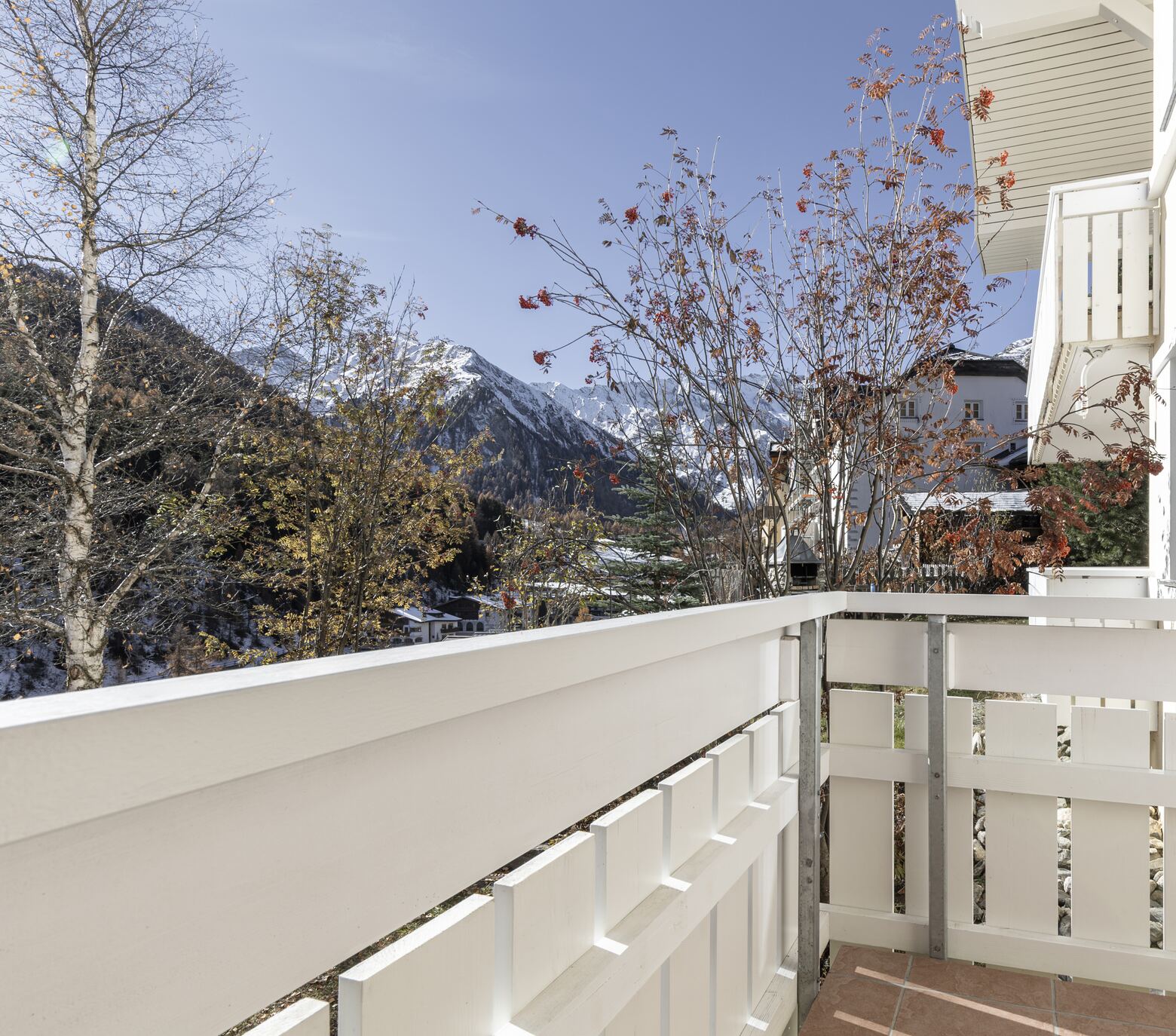 Balkon mit weissem Holzgeländer und Blick auf die Berge