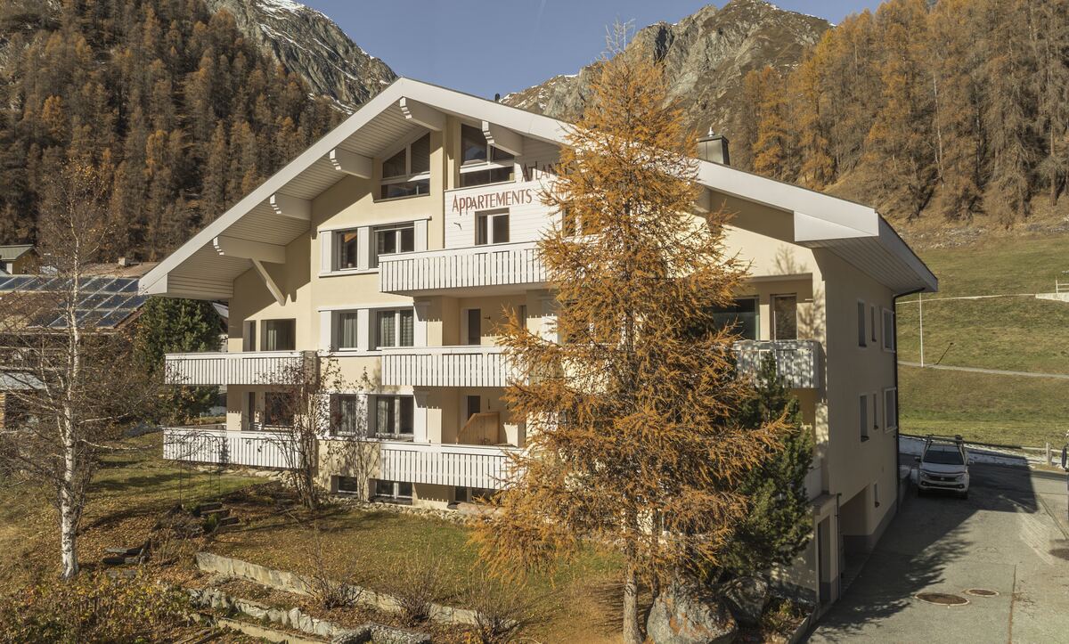 Das Haus im Herbst mit Balkonen, Lärchen und Bergen im Hintergrund