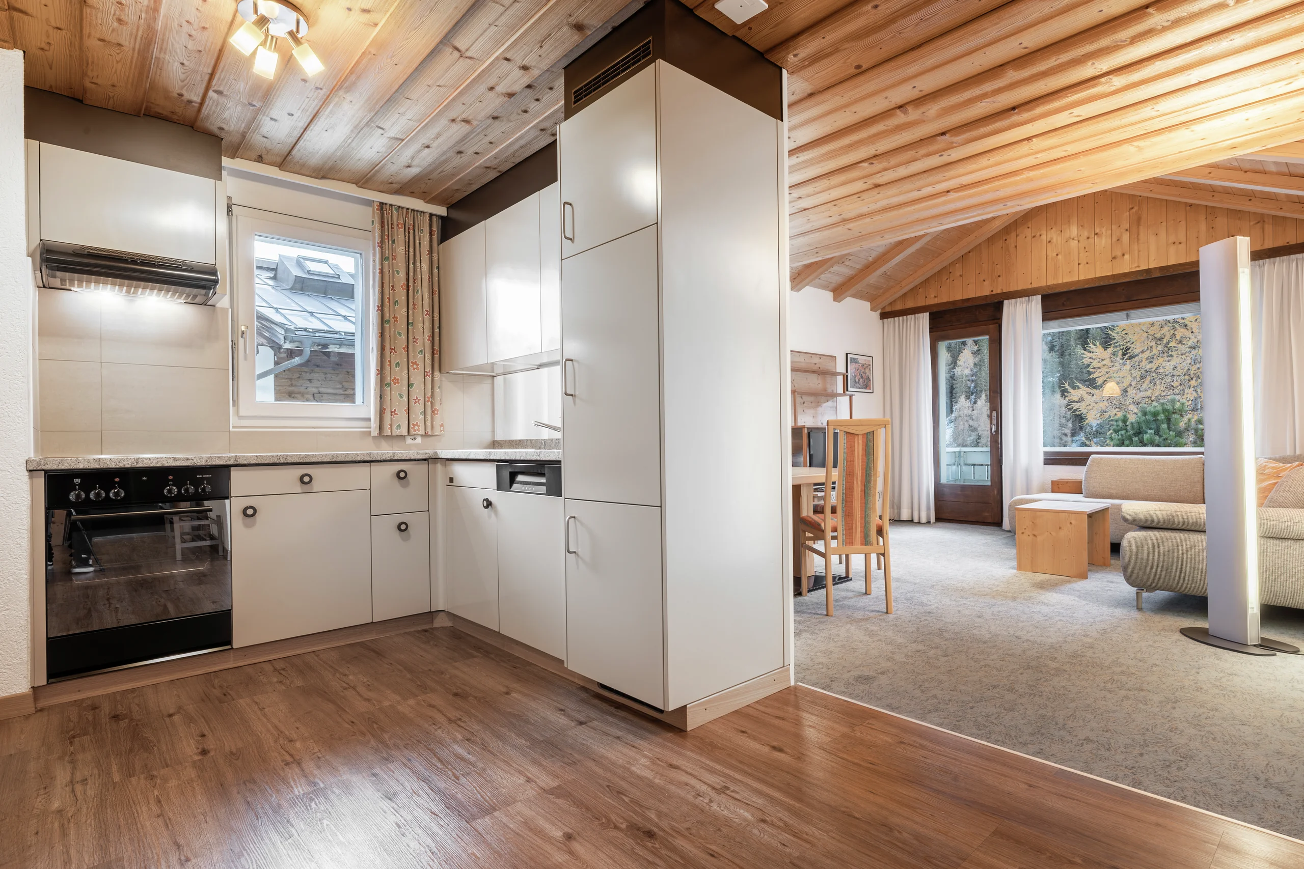 Küche mit hellen Fronten und Holzdecke, Blick in den Wohnbereich, Wohnung 205
