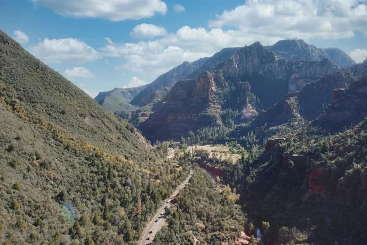 Valley road winding below forested red rock mountains