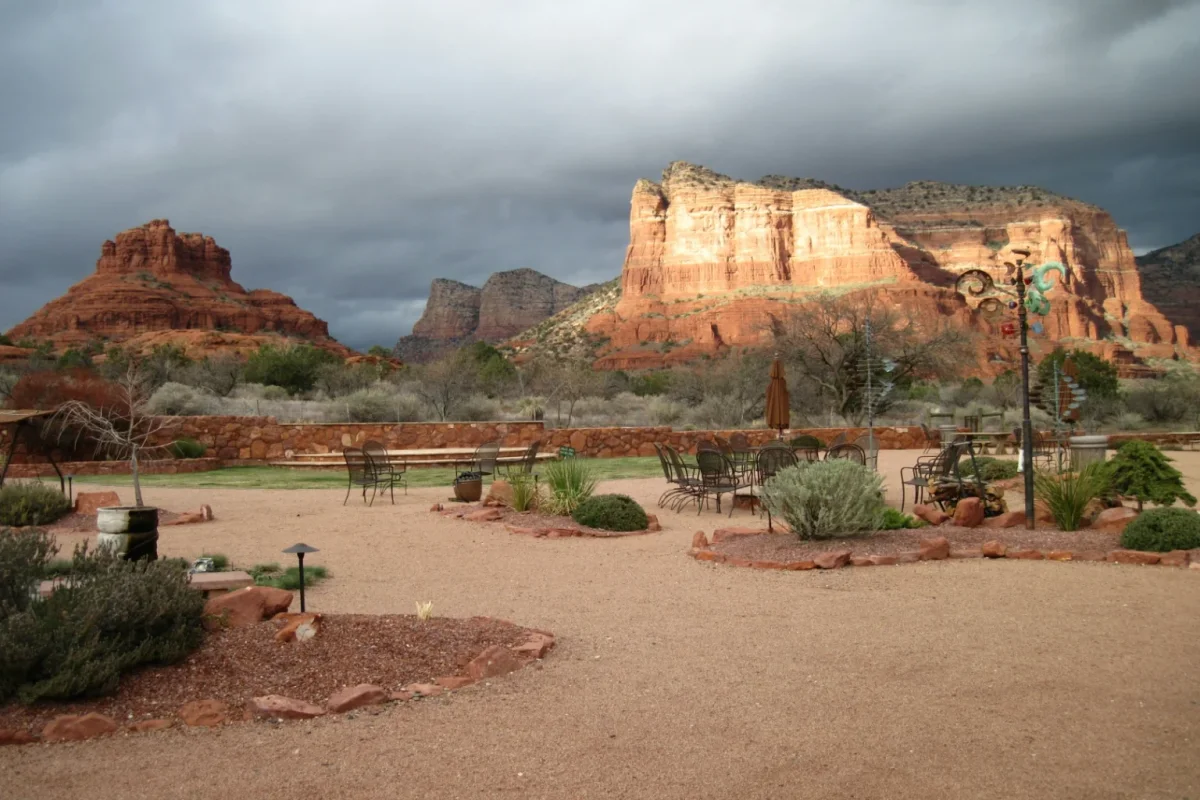 Gravel patio with benches facing Bell Rock and red cliffs under storm clouds