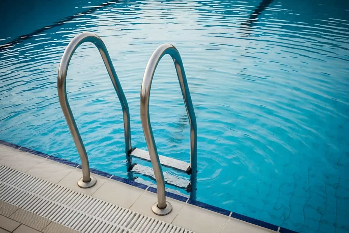 Stainless steel ladder leading into a clear blue swimming pool