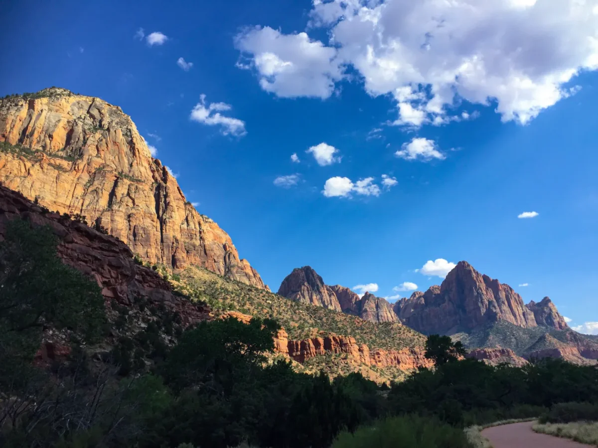 Tall sandstone cliffs and peaks glowing in sunlight under scattered clouds