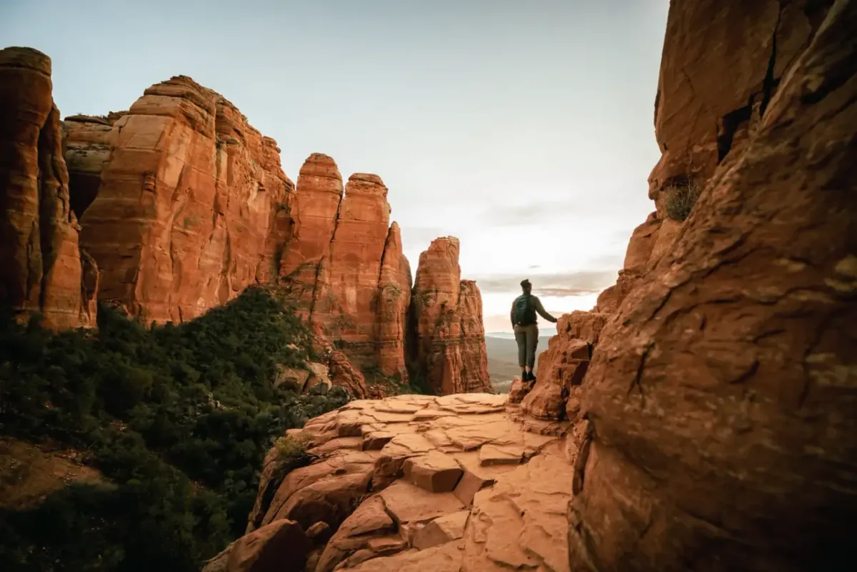 Hiker standing among towering red rock spires at sunset