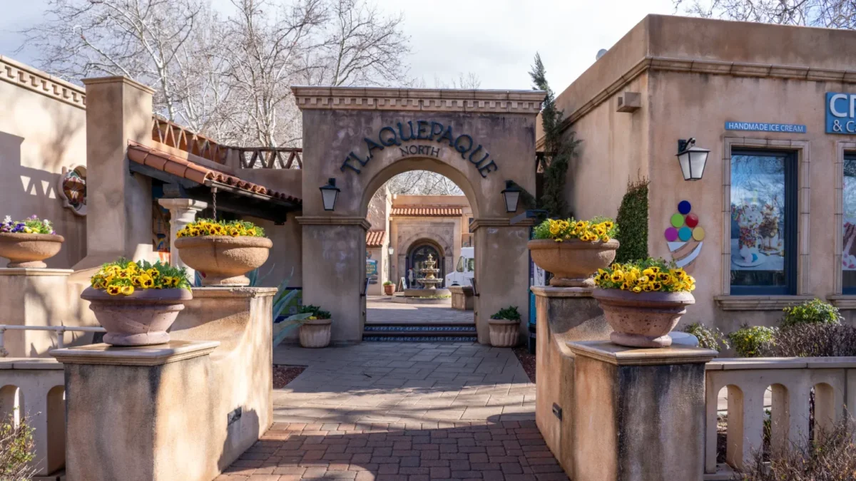 Stone archway entrance to Tlaquepaque with potted yellow flowers