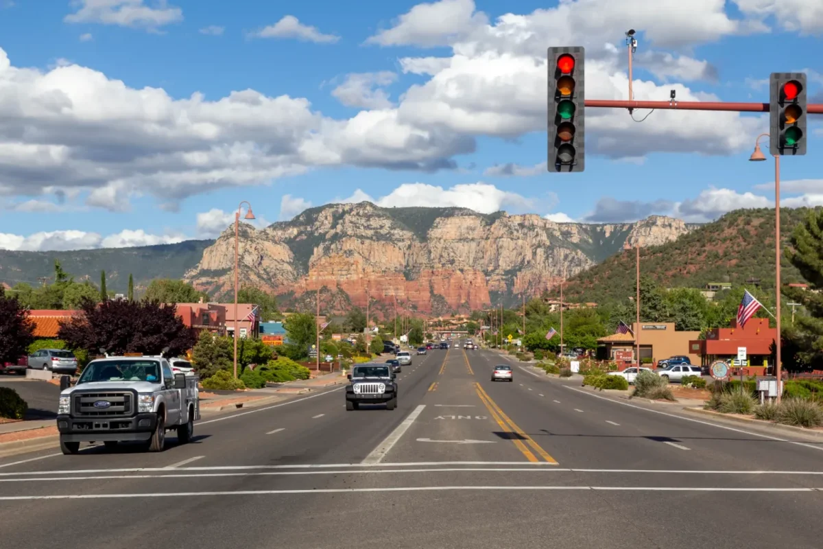 Traffic lights over a town road leading toward red rock cliffs