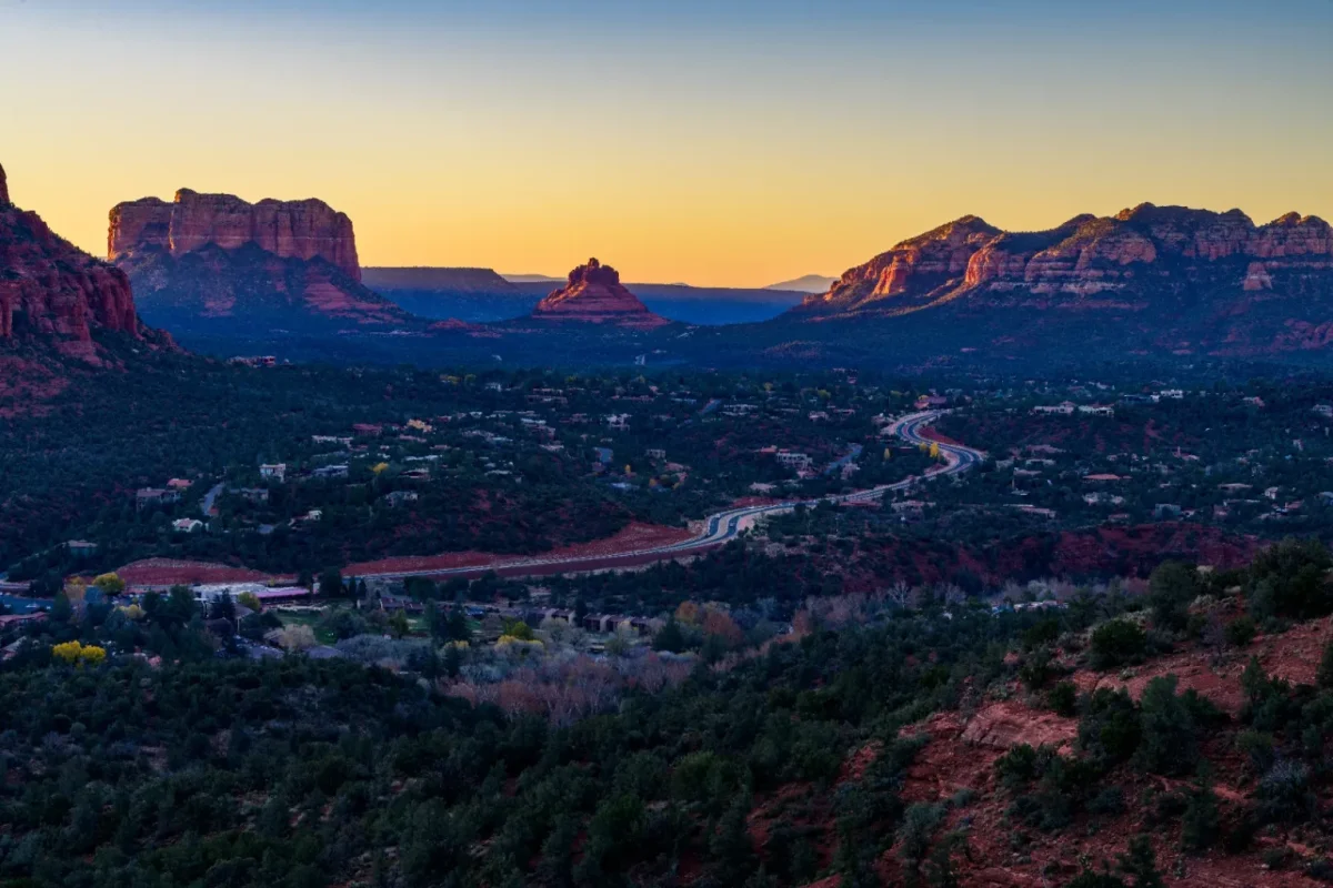 Valley of red rock buttes and a winding road glowing at dusk