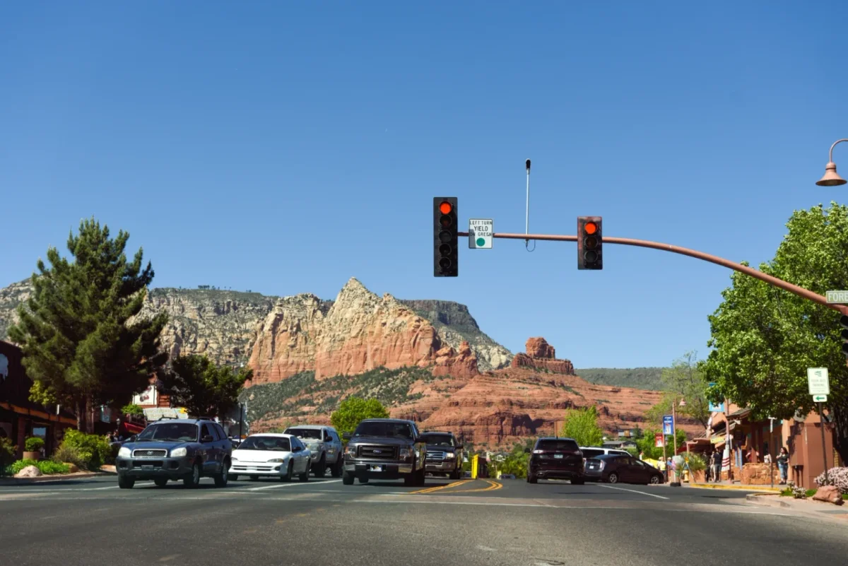Traffic lights over a busy street with a red rock peak rising behind
