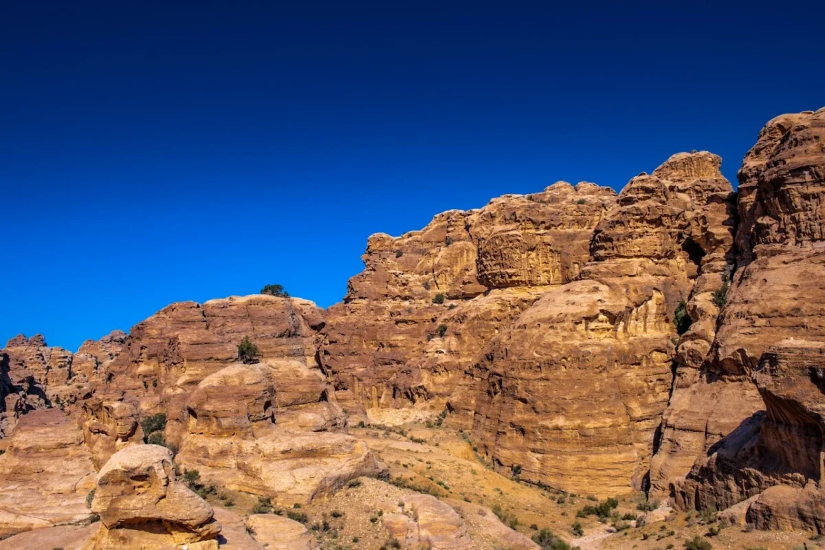 Weathered tan sandstone cliffs against a deep blue sky