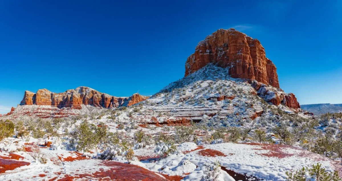 Snow-dusted red rock butte under a bright blue winter sky