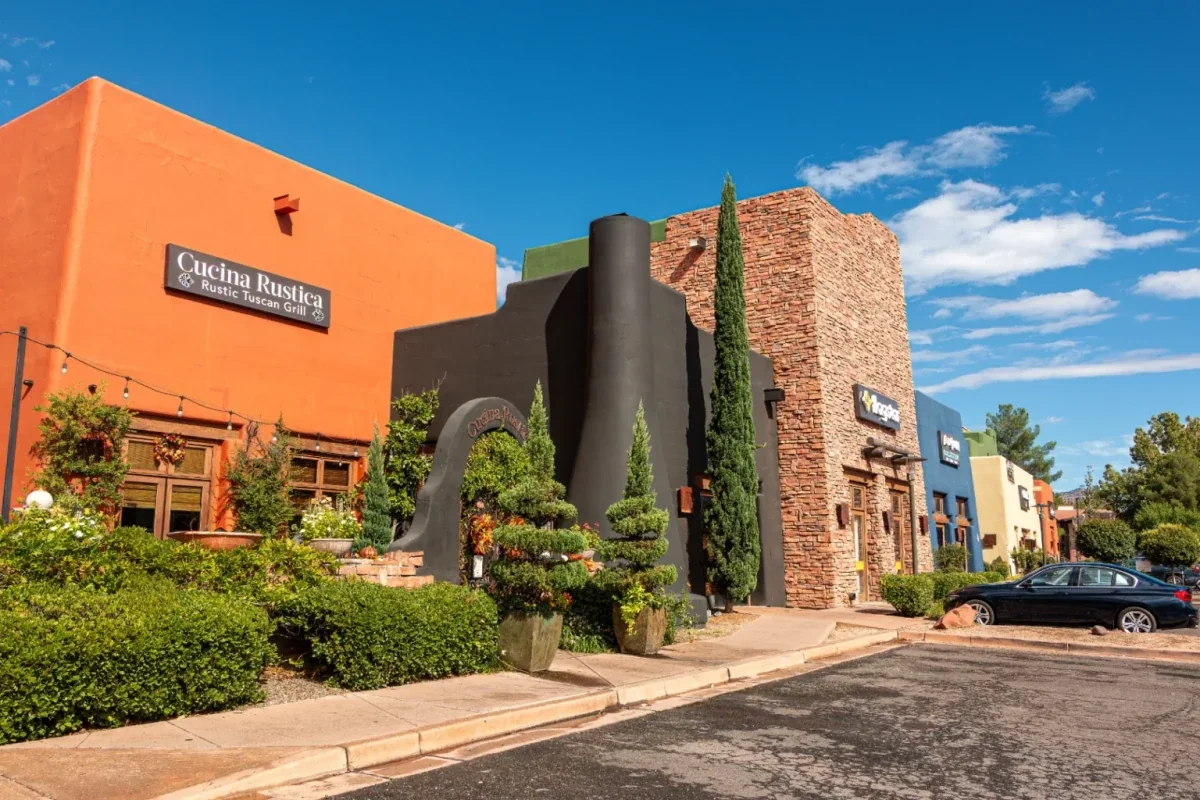Restaurant storefronts with stucco and stone walls along a parking area