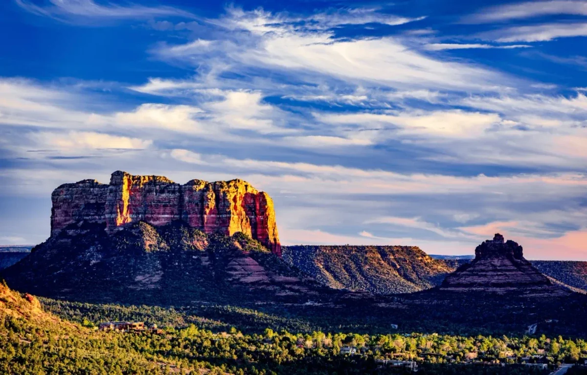 Flat-topped red butte lit by low sun under streaks of cloud