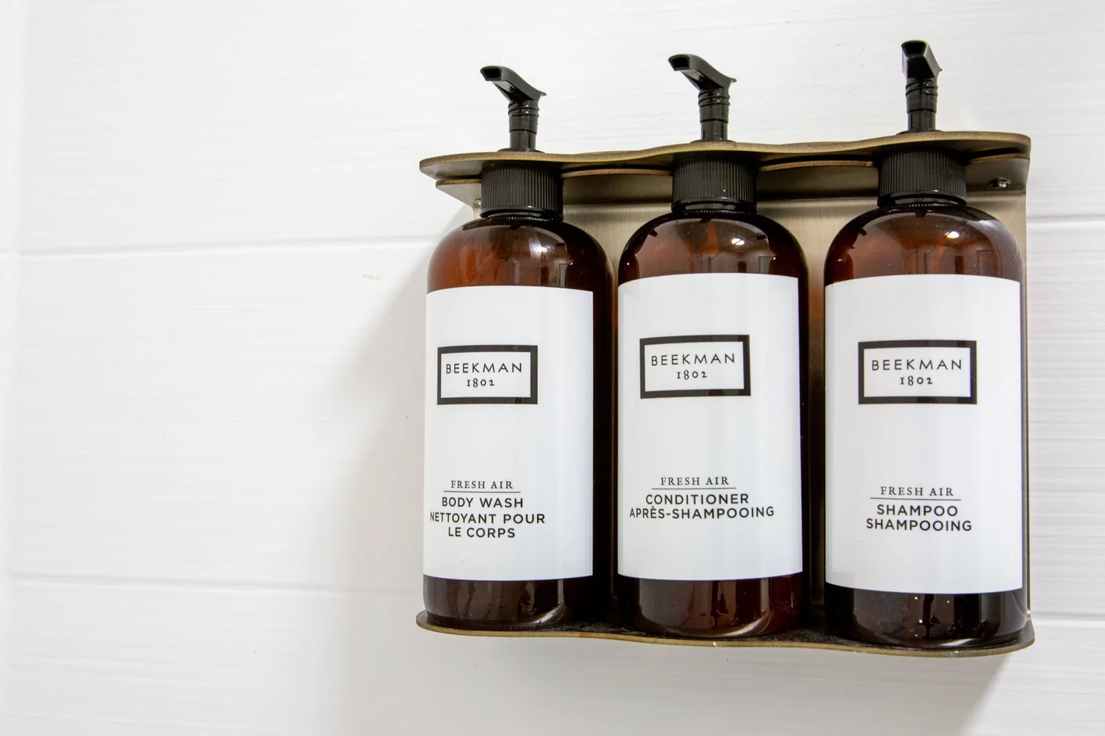 Three wall-mounted Beekman 1802 amenity bottles for body wash, conditioner, and shampoo.