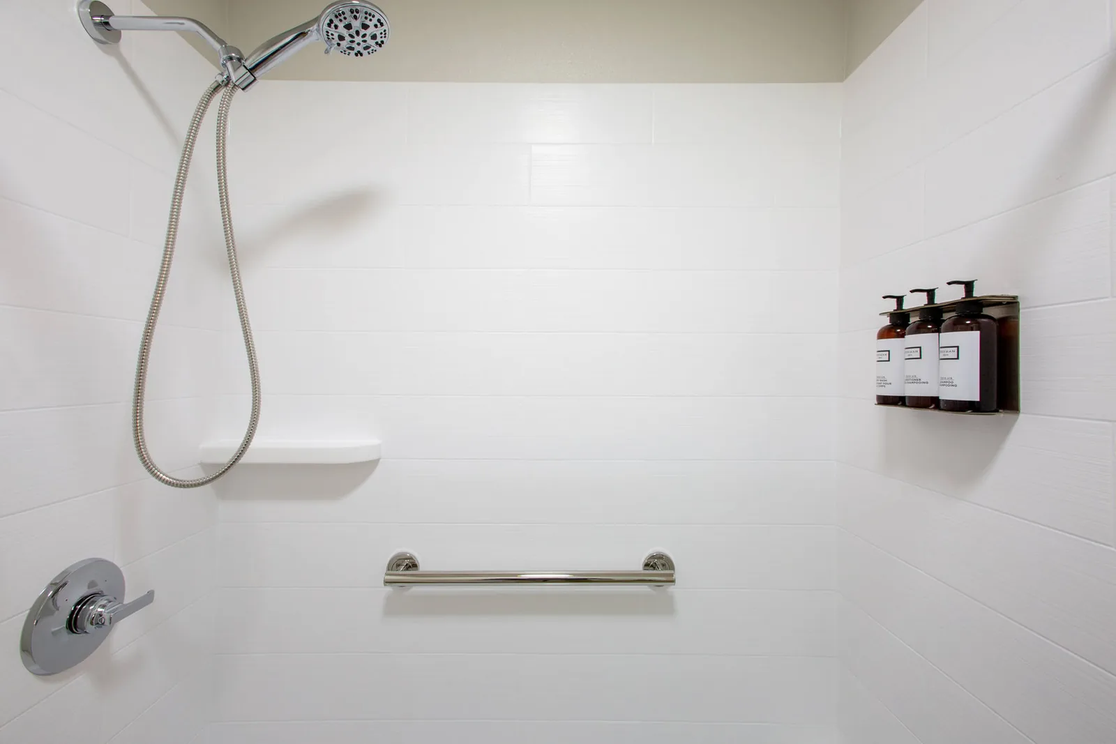 Roll-in accessible shower with a handheld shower head and grab bars.