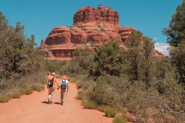 Couple hiking hand in hand toward Bell Rock on a Sedona trail