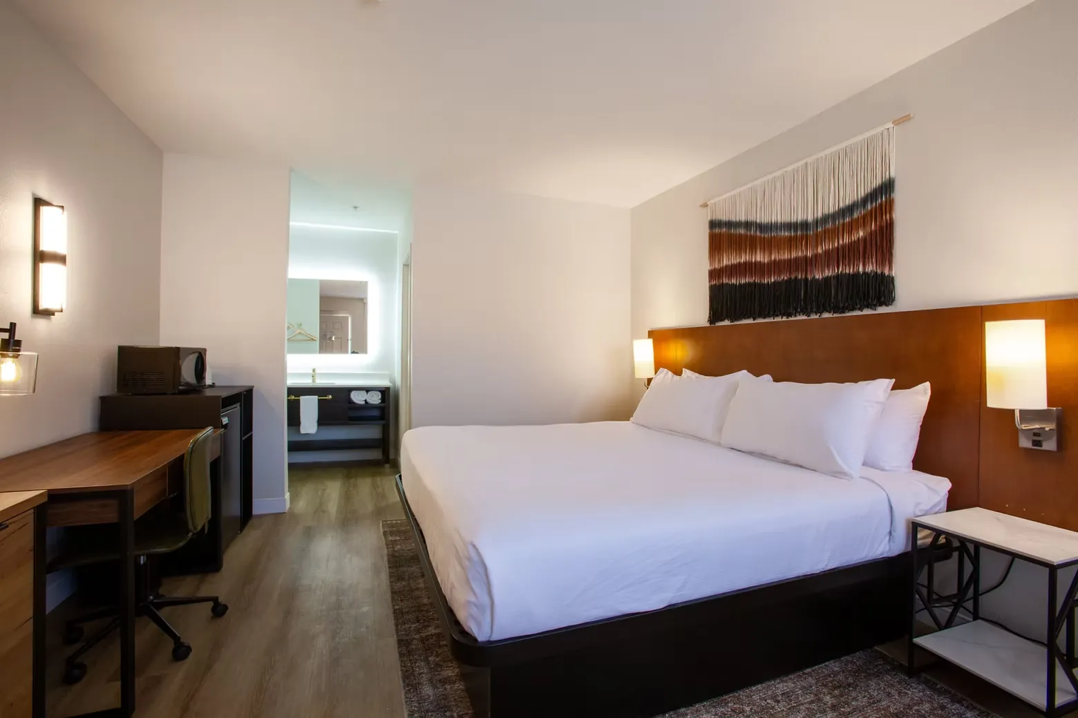 Wide view of the king bed and desk wall, with a cactus print reflected in the mirror.
